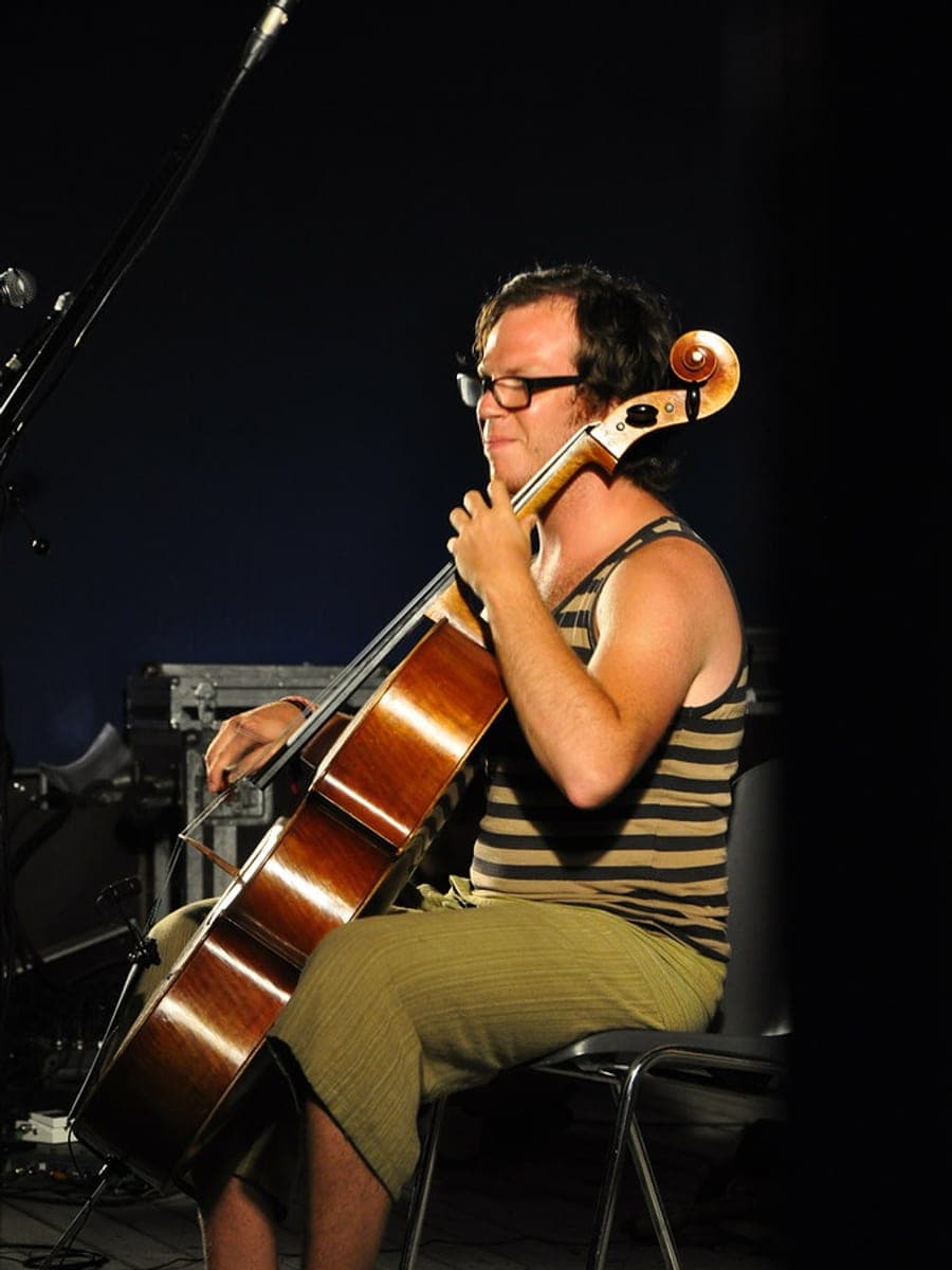 Cellist op een podium, geconcentreerd spelend in het spotlicht.
